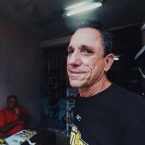 Elderly man smiling indoors at a shoe store with vibrant lighting.