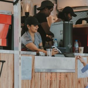 Market scene with diverse individuals at a food stall making a transaction.