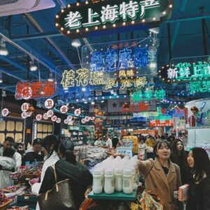 Vibrant indoor market in Shanghai with colorful signs and shoppers exploring local goods.