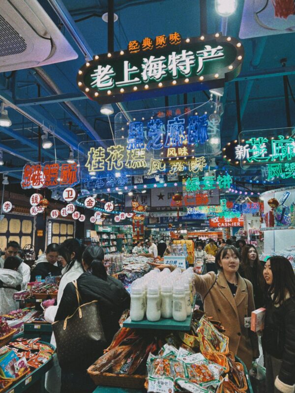Vibrant indoor market in Shanghai with colorful signs and shoppers exploring local goods.